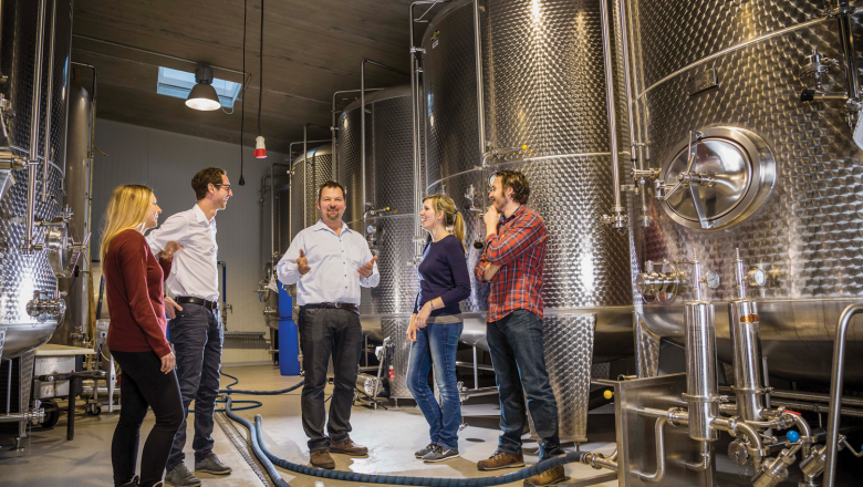 Mohr-Sederl Fruchwelt, © Mohr Sederl Gruppe von Menschen in einer Brauerei mit großen Metalltanks.