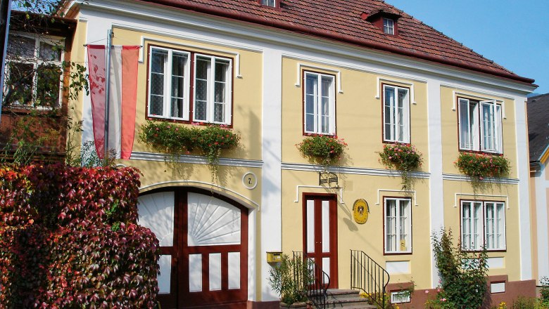 Kaiserpostamt, © Marktgemeinde Payerbach Historisches gelbes Gebäude mit roten Fensterläden und Blumen, beschriftet als Kaiserpostamt.