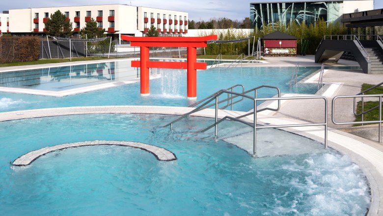 Au&szlig;enpool des Hotel Linsberg Asia mit rotem Torii und modernen Geb&auml;uden im Hintergrund.