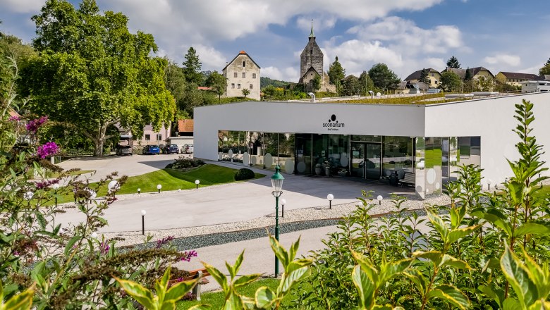 Modernes Gebäude des Sconariums mit Kirche im Hintergrund.