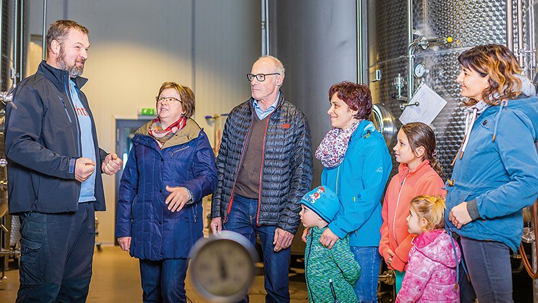 Gruppe von Menschen in einer Fabrikhalle mit gro&szlig;en Metalltanks.